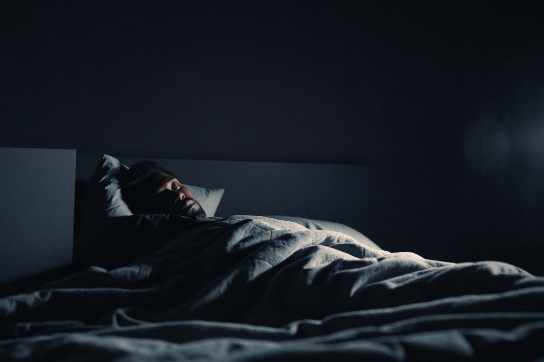 A man asleep in a dark, calm bedroom at night