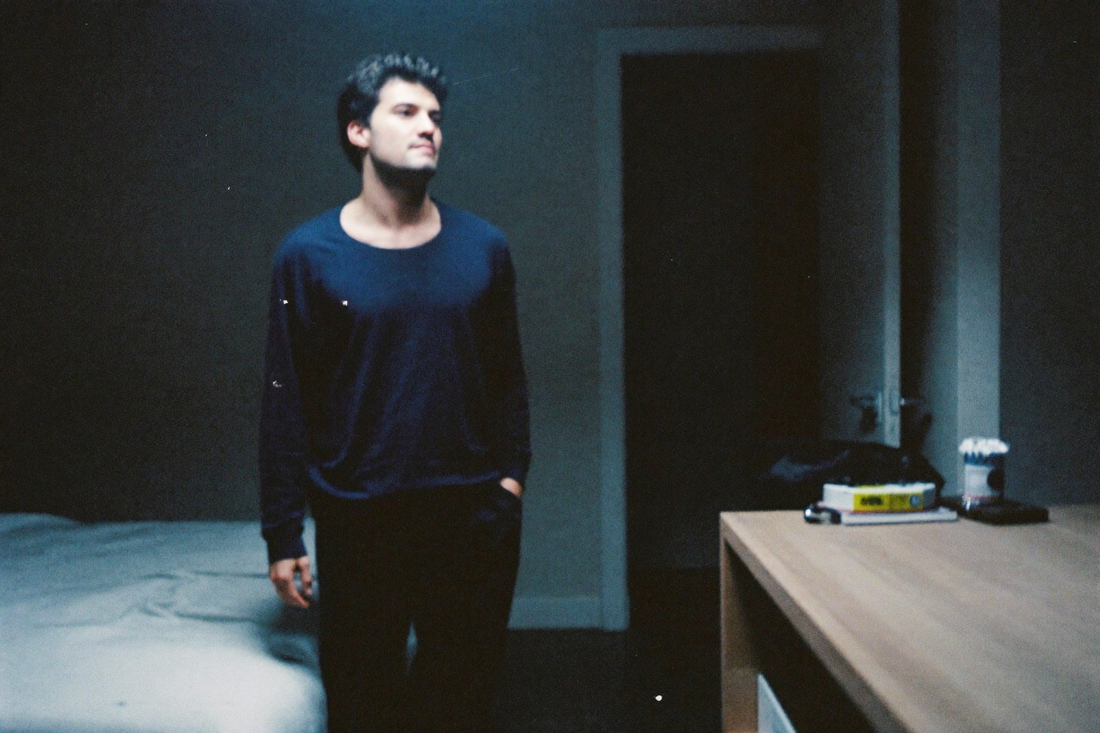 A man in loungewear during an evening wind-down in a dim bedroom